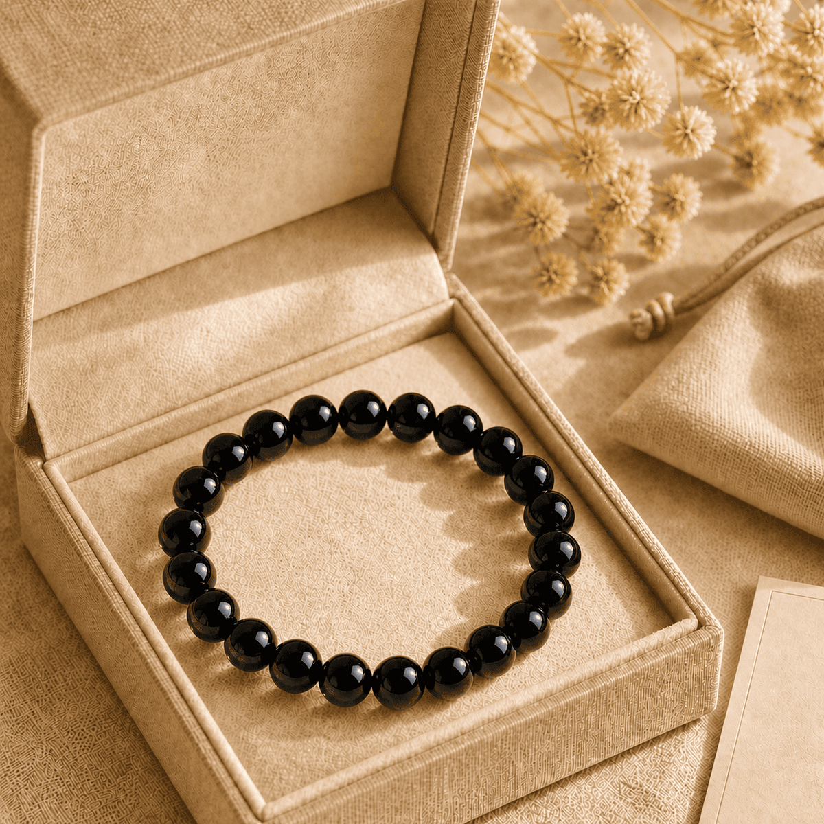 Black obsidian bracelet presented in a beige gift box with a matching drawstring pouch