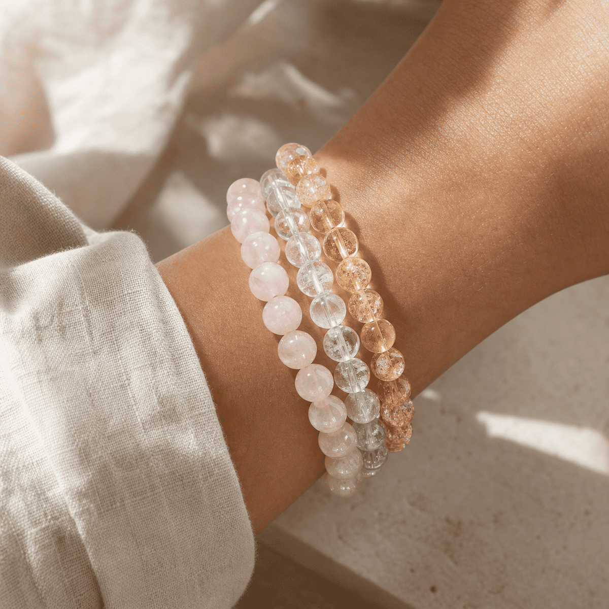 Stacked rose quartz clear quartz and citrine crystal bead bracelets worn on the wrist