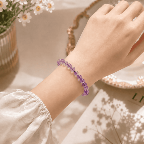 Amethyst crystal bracelet for women worn on the wrist in a floral setting