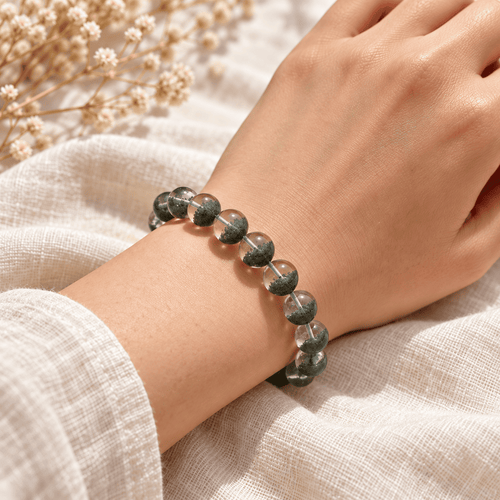 Green phantom bracelet worn on a wrist, showing clear round beads with deep-green inclusions