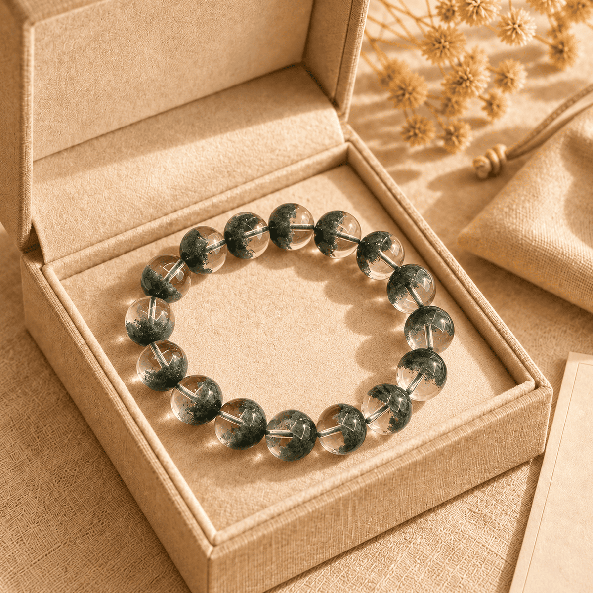 Green phantom crystal bracelet with clear round beads and deep-green inclusions in an open gift box