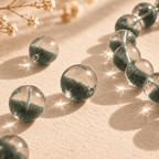 Close-up of green phantom quartz beads showing clear upper sections, dense green inclusions and drilled holes