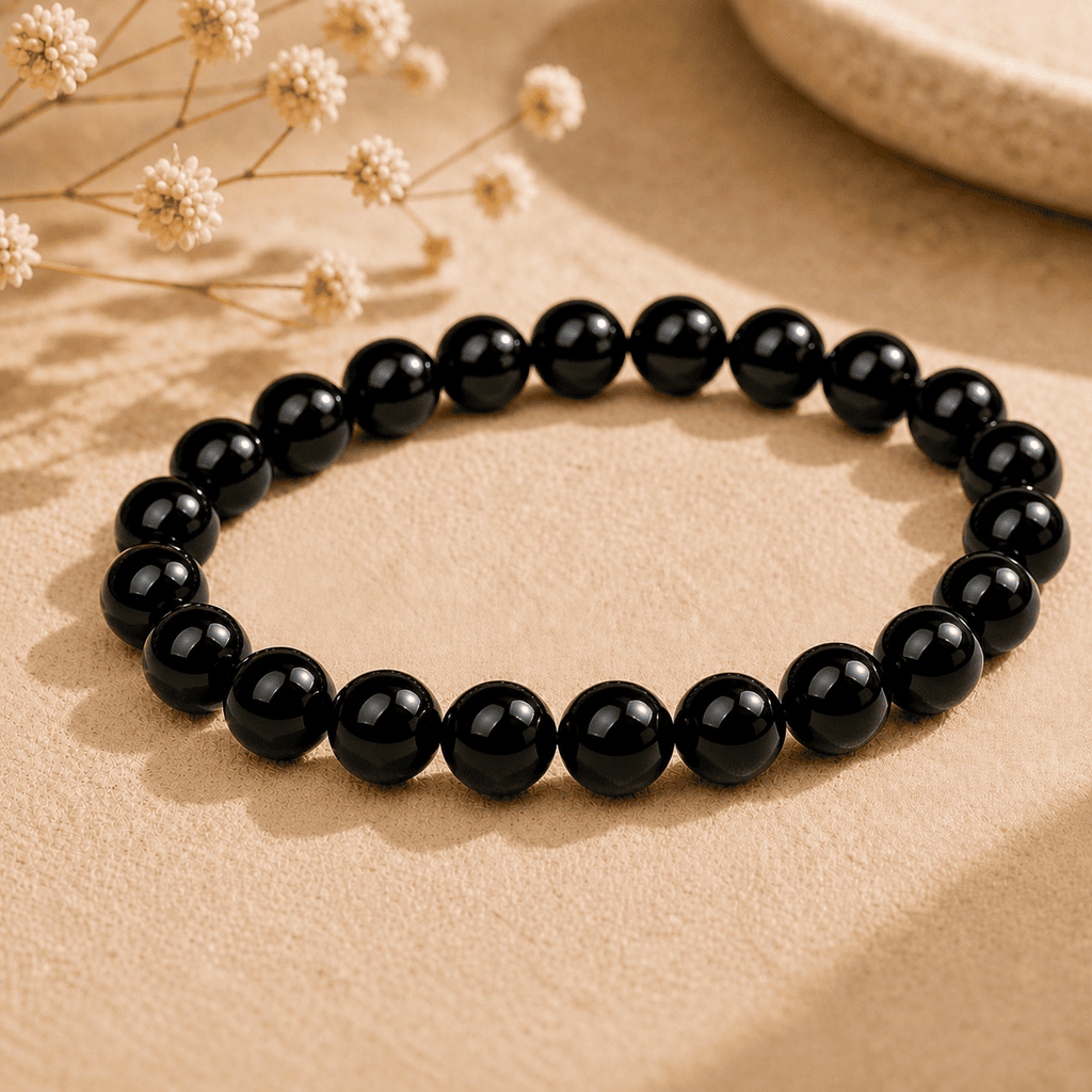 Men's black crystal bracelet with polished obsidian beads styled in warm natural light