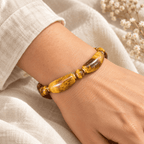 Men's tiger eye bracelet with curved golden-brown beads and gold-tone spacers worn on a wrist