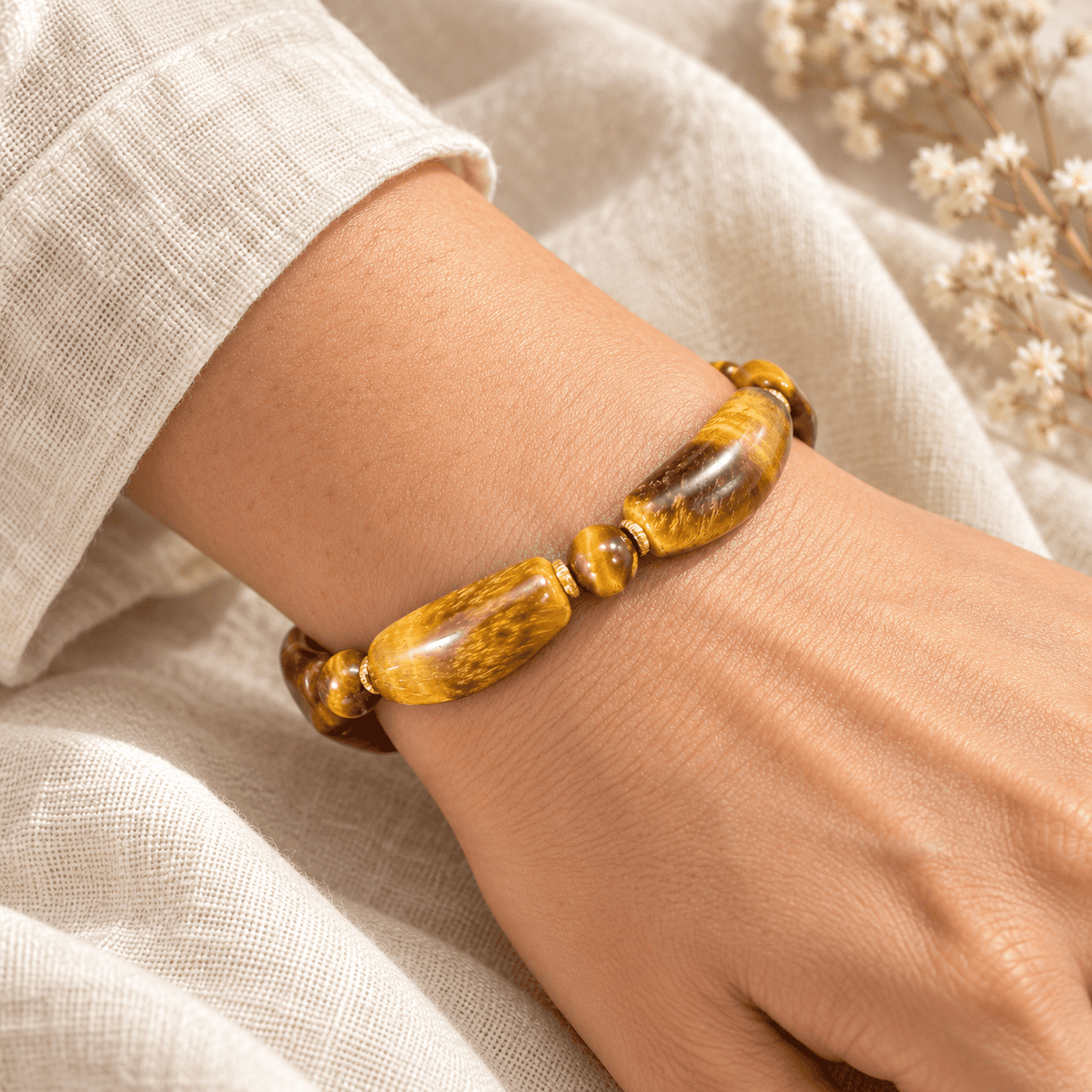 Men's tiger eye bracelet with curved golden-brown beads and gold-tone spacers worn on a wrist