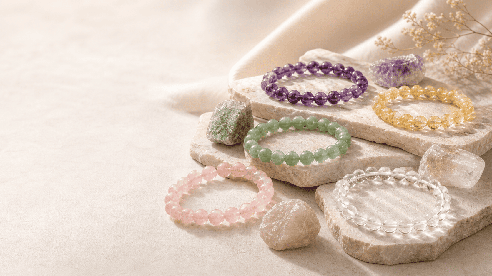 Natural Crystals crystal bracelets collection with amethyst, citrine, rose quartz, green crystal, and clear quartz bead bracelets on stone trays