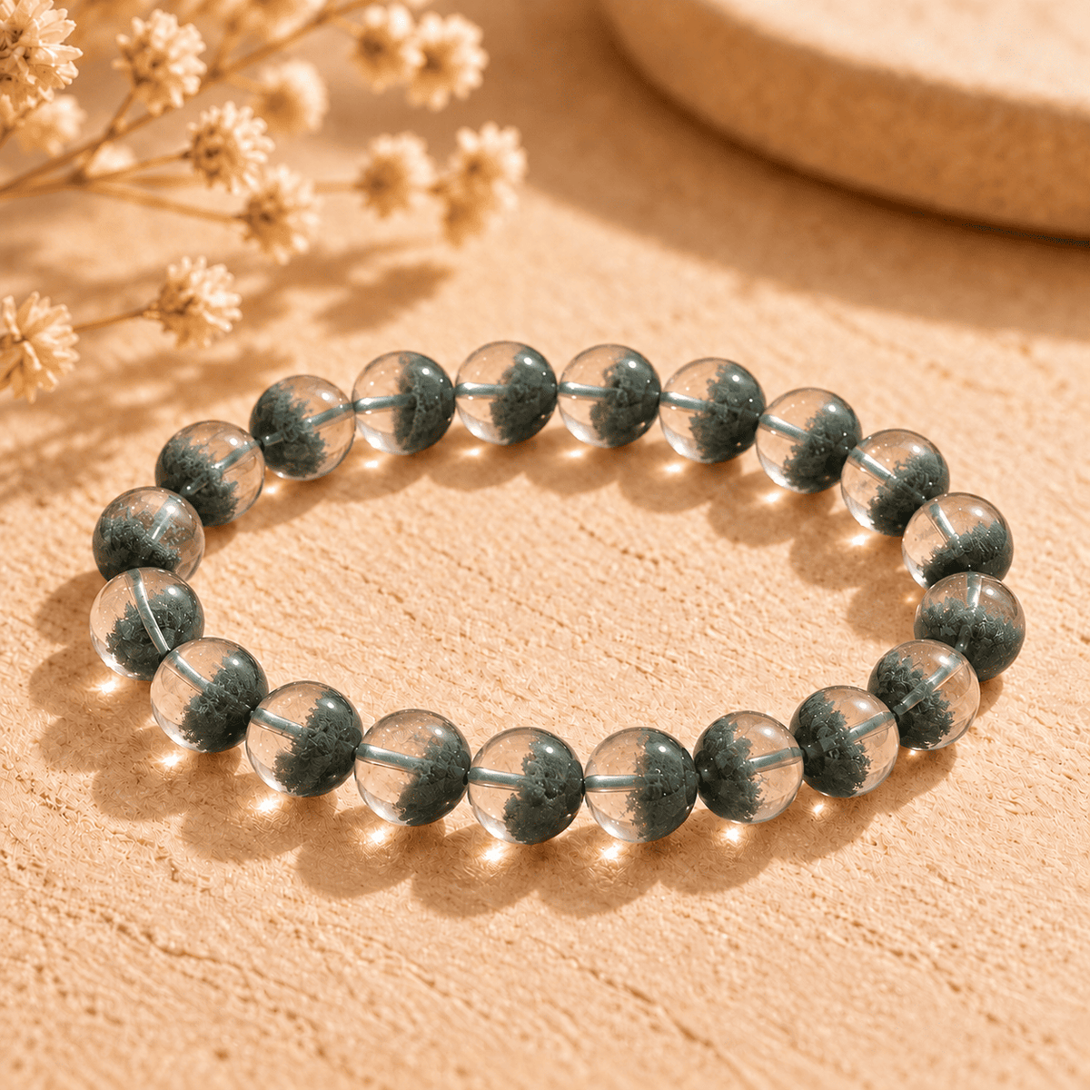 Phantom quartz bracelet with green inclusions clustered in the lower half of clear round beads in sunlight