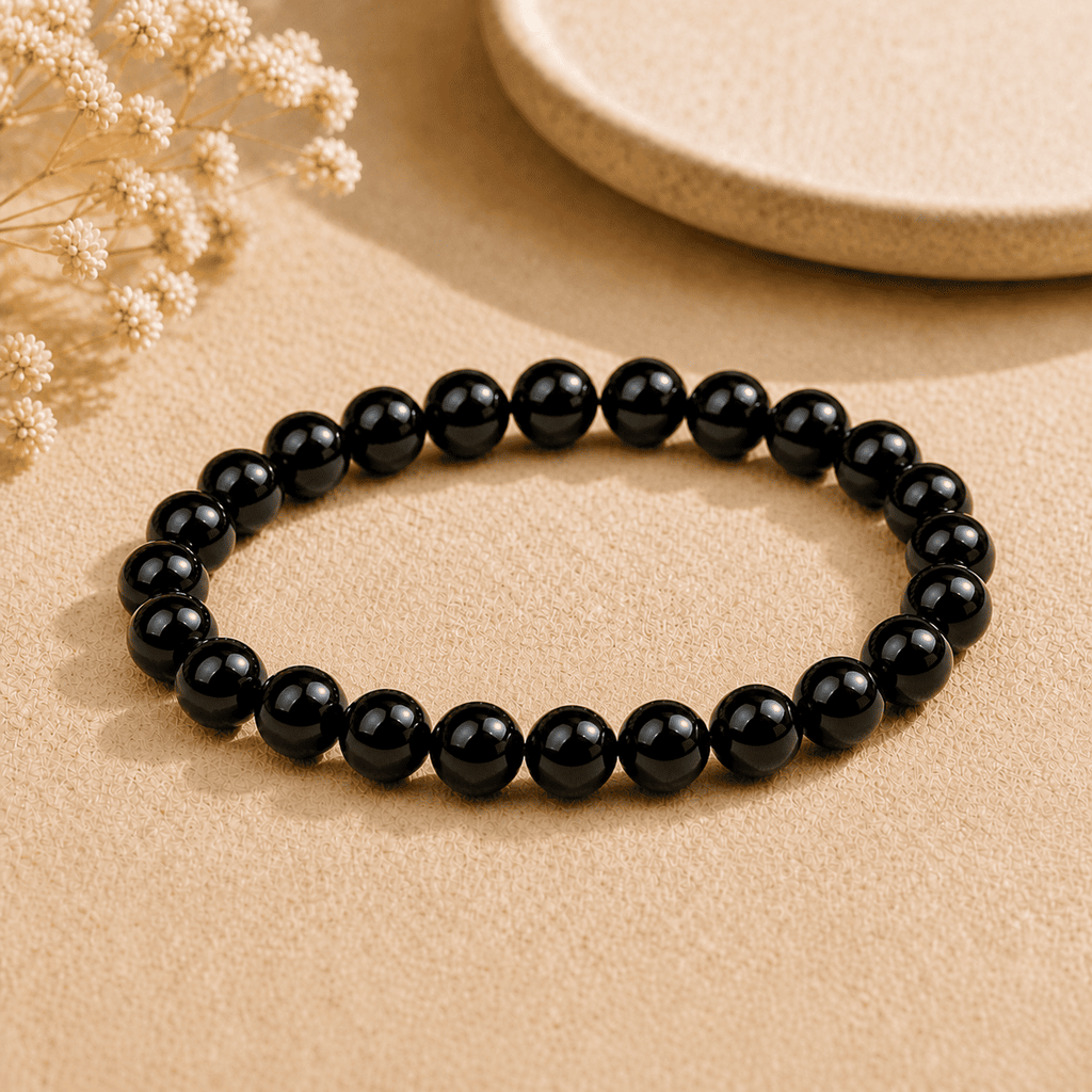 Real black obsidian bracelet with polished round beads displayed on neutral fabric