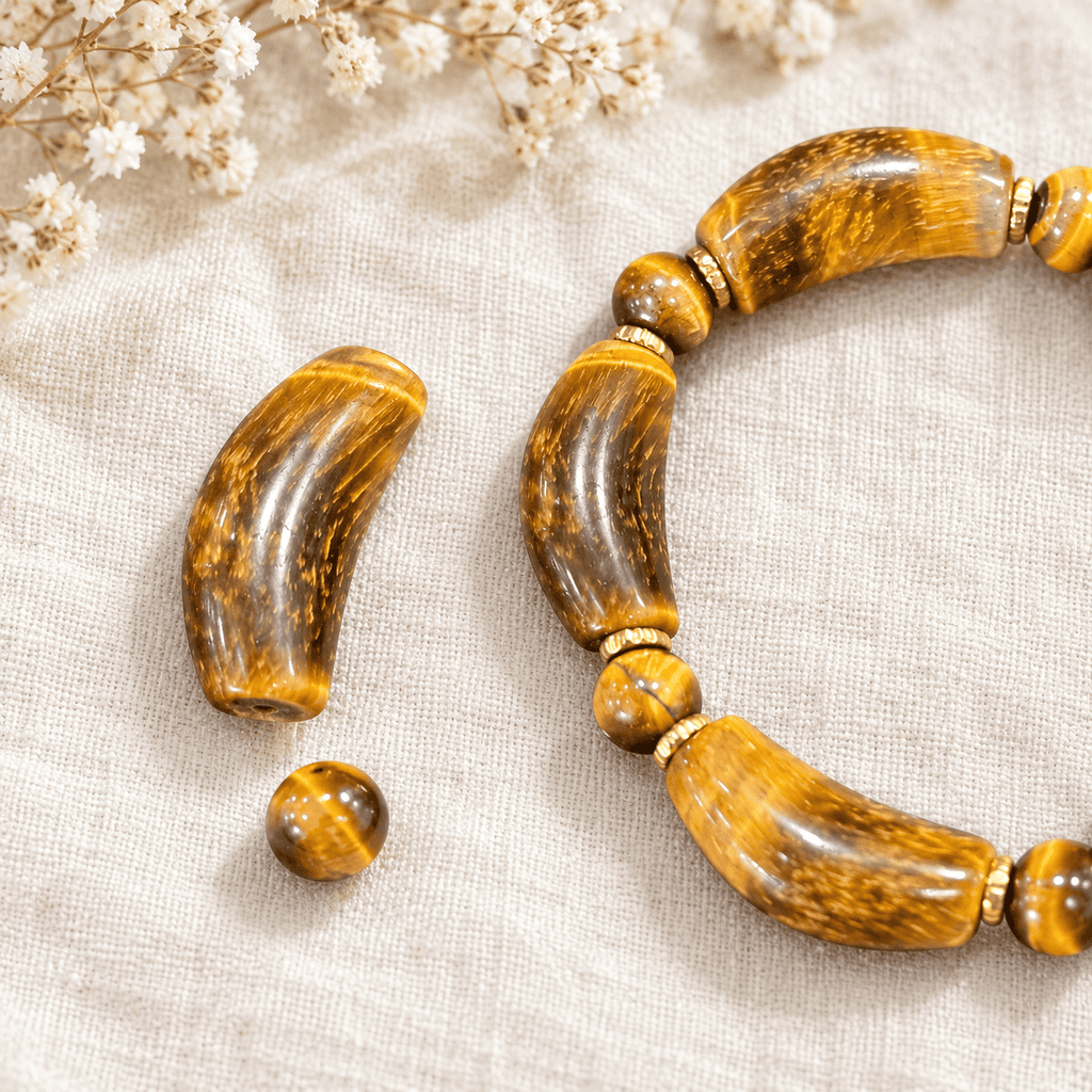 Tiger eye bracelet bead detail with loose curved and round beads beside gold-tone spacers on linen
