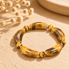Tiger eye stone bracelet with golden-brown curved beads, round beads and gold-tone spacers on a sunlit surface
