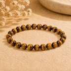 Tigers Eye Bracelet with polished golden brown round beads displayed on neutral fabric in warm light